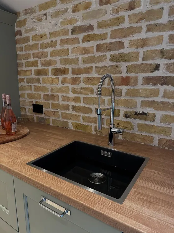 Black kitchen sink with a pull-down tap on an oak worktop