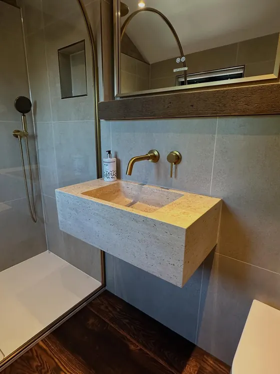 Brushed brass tap over a stone basin