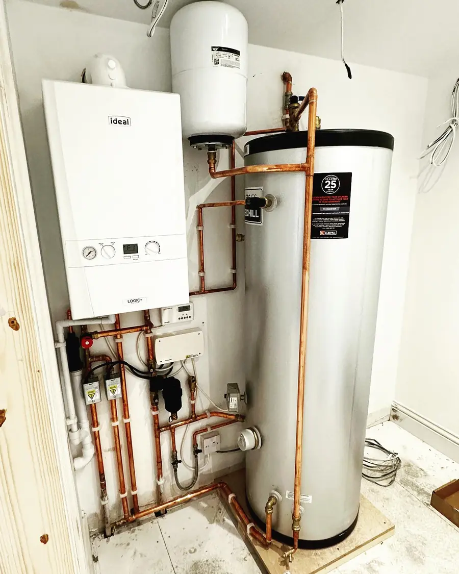 A bright, newly fitted boiler and hot water cylinder with neat copper pipework, by Addisons