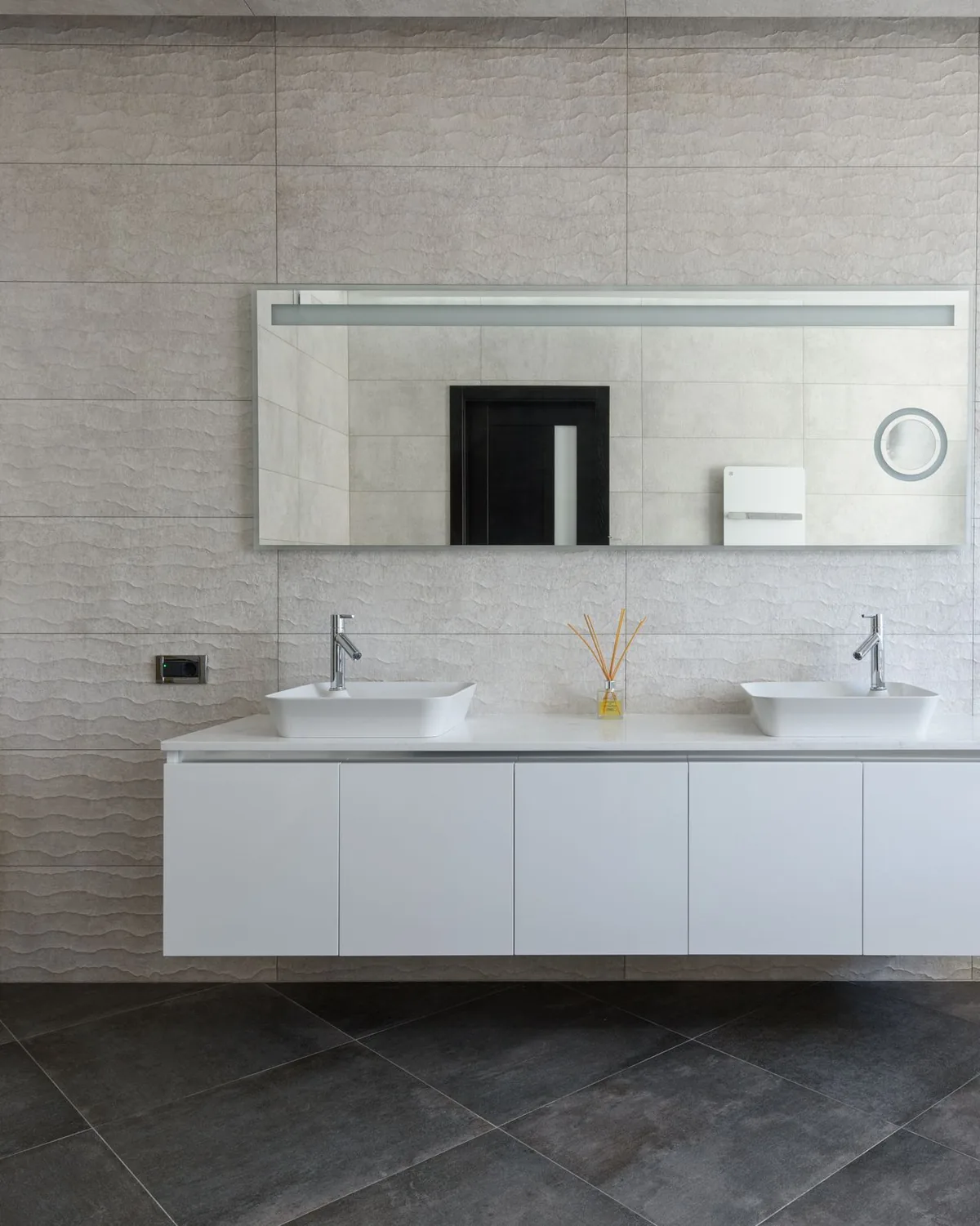 A modern bathroom with a white double vanity unit, a wide mirror and matte grey tiles